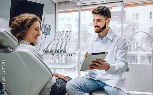 Fototapeta na szkło Ludzi, medycyny, stomatology i opieki zdrowotnej pojęcie, - szczęśliwy męski dentysta pokazuje pastylka komputer kobieta pacjent przy stomatologicznym kliniki biurem.