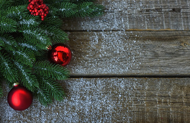 Christmas background for greeting card with Christmas tree branches, decoration and red balls, on on dark wooden board. Top view with copy space for text.