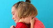 Mother calms baby on blue background. Young woman soothes crying son