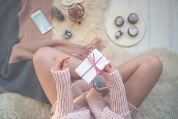 Girl holding a small gift box wrapped white paper. Happy Christmas or New Year. Preparing gifts for christmas. Spending time, celebrating a holiday at home. Winter and people concept. Top view. Toned.