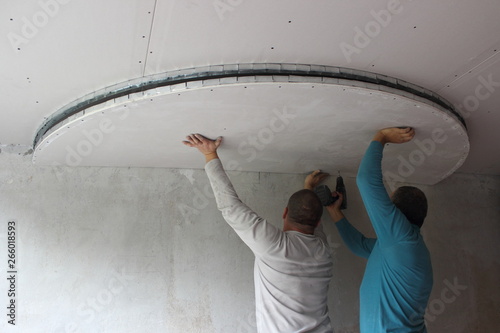 Two Male Builders Install A Figured Element Of The Suspended