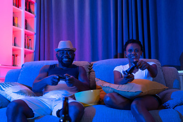 Happy African couple playing video games on console