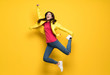 Teenager girl jumping over isolated yellow wall