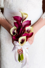 Wall Mural - Unrecognizable bride holding a refined wedding bouquet of white and crimson callas