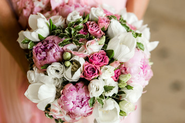 Wall Mural - Unrecognizable bride holding a refined wedding bouquet of pink roses and peonies with white eusmoy and tulips