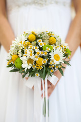 Wall Mural - Romantic bouquet of daisies in the hands of an unrecognizable bride