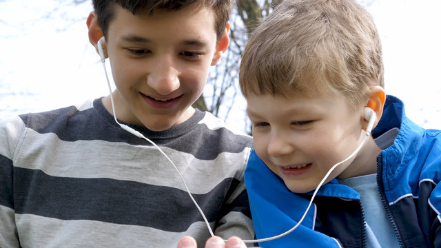 teen boys with smart phone listening or talking in british park. low angle shot teenager and social media concept