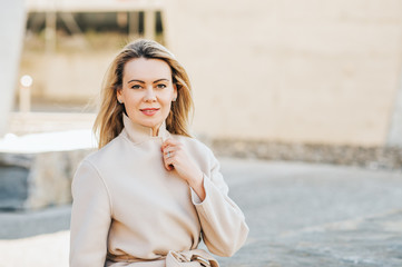 Wall Mural - outdoor portrait of beautiful blond woman wearing beige belted coat