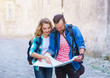 © Acronym - Young travelers with a tourist map. Man and woman having vacation. Backpackers, traveling and tourism concept.