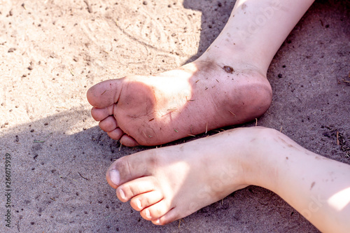 Fotografía Holiday concept of dirty child feet on dirty soil