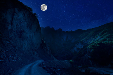 Wall Mural - mountain road through the forest on a full moon night. scenic night landscape of country road at nig