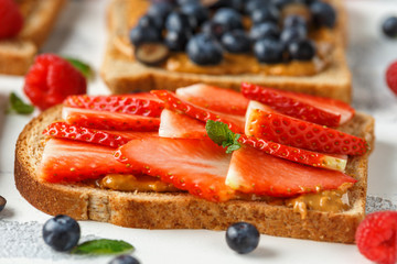 Wall Mural - Peanut butter sandwiches with fresh strawberry, blueberry, raspberry and banana whole meal toasts.