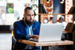 © Ilnur - Businessman bearded man in a suit works behind the laptop sitting in a comfortable office coworking.