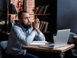 © Ilnur - Businessman bearded man in a suit works behind the laptop sitting in a comfortable office coworking.
