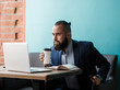 © Ilnur - Young serious bearded businessman working on computer at table,drinking coffee.Man analyzes information, data, develops business plan. Freelancer, entrepreneur.Online marketing, education, e-learning