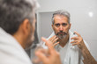 © cherryandbees - middle aged bearded gray haired man applying perfume in bathroom