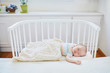 Baby sleeping in co-sleeper crib attached to parents' bed
