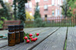Ätherische Öle auf Holztisch mit Johanniskrautfrucht und Garten im Hintergrund