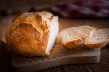 Sliced loaf of wheat bread on wooden table