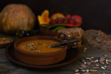 Wall Mural - Vegetables cream soup and ingredients. Concept of healthy eating or vegetarian food. Dietary vegetarian pumpkin cream soup puree, on dark brown wooden table. Copy space. Toned image. Soft focus.