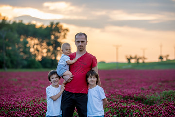 Poster - Father, having his portrait with his three sons, boys, in crimson clover field on sunset