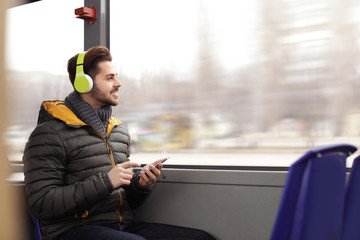 Young man listening to music with headphones in public transport