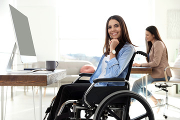 Poster - Young woman in wheelchair using computer at workplace