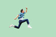 canvas print picture - Jump to the success. Full length profile side view of active young man in casual blue checkered shirt and headband running very fast or jumping. indoor studio shot, isolated on green background.