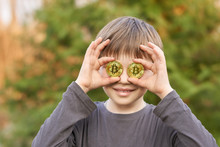 The boy tries on the eye bitcoin coin in the summer in the Park