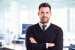 © sepy - Casual businessman portrait while standing in the office with folded arms