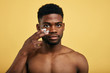 shirtless young brutal african american man applying facial cream on his cheek. close up portrait,men's beauty. skin care