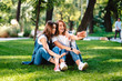 © teksomolika - Two female friend sitting in the park have a rest take a selfie