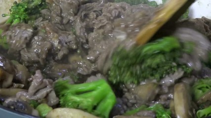 Canvas Print - Stirring beef and broccoli close up, slow motion