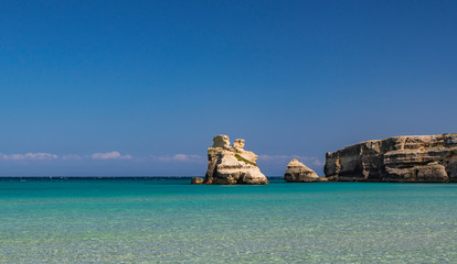 The bay of Torre dell'Orso, with its high cliffs, in Salento, Puglia, Italy. Turquoise sea and blue sky, sunny day in summer. The stacks called the Two Sisters, immersed in the sea.