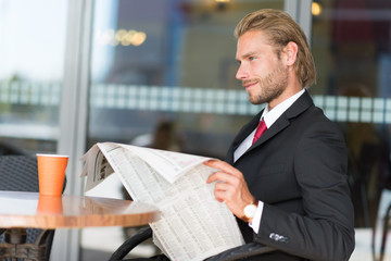 Businessman reading newspaper in a cafe