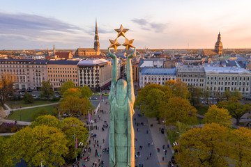 Wall Mural - Beautiful sunset view over Riga by the statue of liberty - Milda in Latvia. The monument of freedom. People gathering around the monument for the concert.