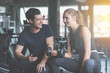 © CasanoWa Stutio - Young woman sitting on a stool with personal trainer, Trainer making fitness for female client at gym