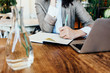 © Alex from the Rock - Woman writing down notes with pen, sitting in cafe with laptop. Wooden natural table