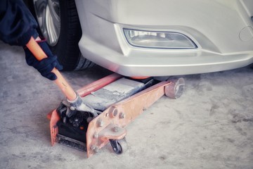 Car care , The car mechanic is lifting the car with the hydraulic Floor Jack. (Spot focus)