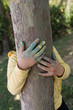 © Fertas - the child paint her hands and hug the tree with finger paint.