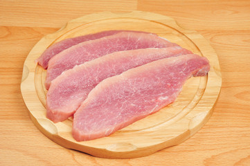 Raw pork meat sliced on a board, on an isolated wooden background