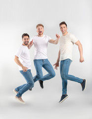 Wall Mural - Jumping young men on light background