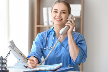 Poster - Young medical assistant talking by phone in clinic