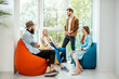 © rh2010 - Group of diverse people having a conversation during the coffee break sitting on the colorful poufs near the window in the office