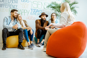 Wall Mural - Two young couples sitting during the psychological therapy with psychologist, solving some mental problems in the modern office