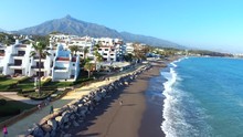 Aerial View Flying Over Coast Line Of Golden Mile, Marbella,Spain.
Area Known As The Costa Del Sol, Known For Vacation And Holidays.shot Shows Beach People Walking And Mountain Perfect Composition