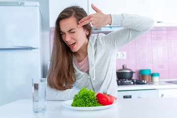 Wall Mural - Sad unhappy woman is tired of dieting, exterminate yourself with a diet and forcing yourself to eat organic, clean healthy food