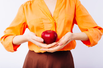 Girl in a bright orange sweater with an apple in her hands promotes healthy food. 