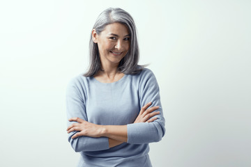 Wall Mural - Beautiful Asian with white hair smiling standing near the wall