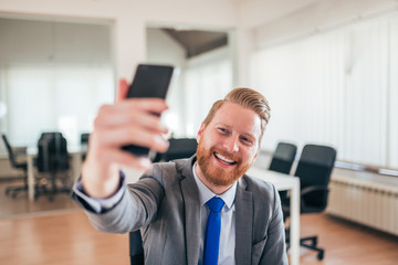 Wall Mural - Happy businessman taking selfie at work.